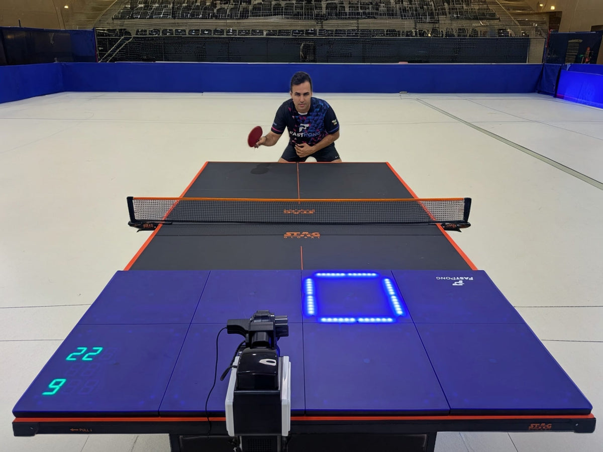A table tennis player using the Fastpong system for table tennis practise in a large sports hall