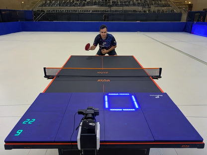 A table tennis player using the Fastpong system for table tennis practise in a large sports hall