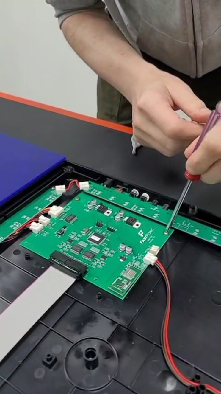 Unscrewing the main PCB from a tile in the Fastpong system