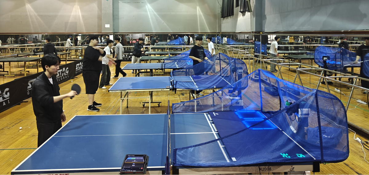 Table tennis students using the Fastpong system to practise in class. The Fastpong app can be seen on a mobile phone screen in the foreground.